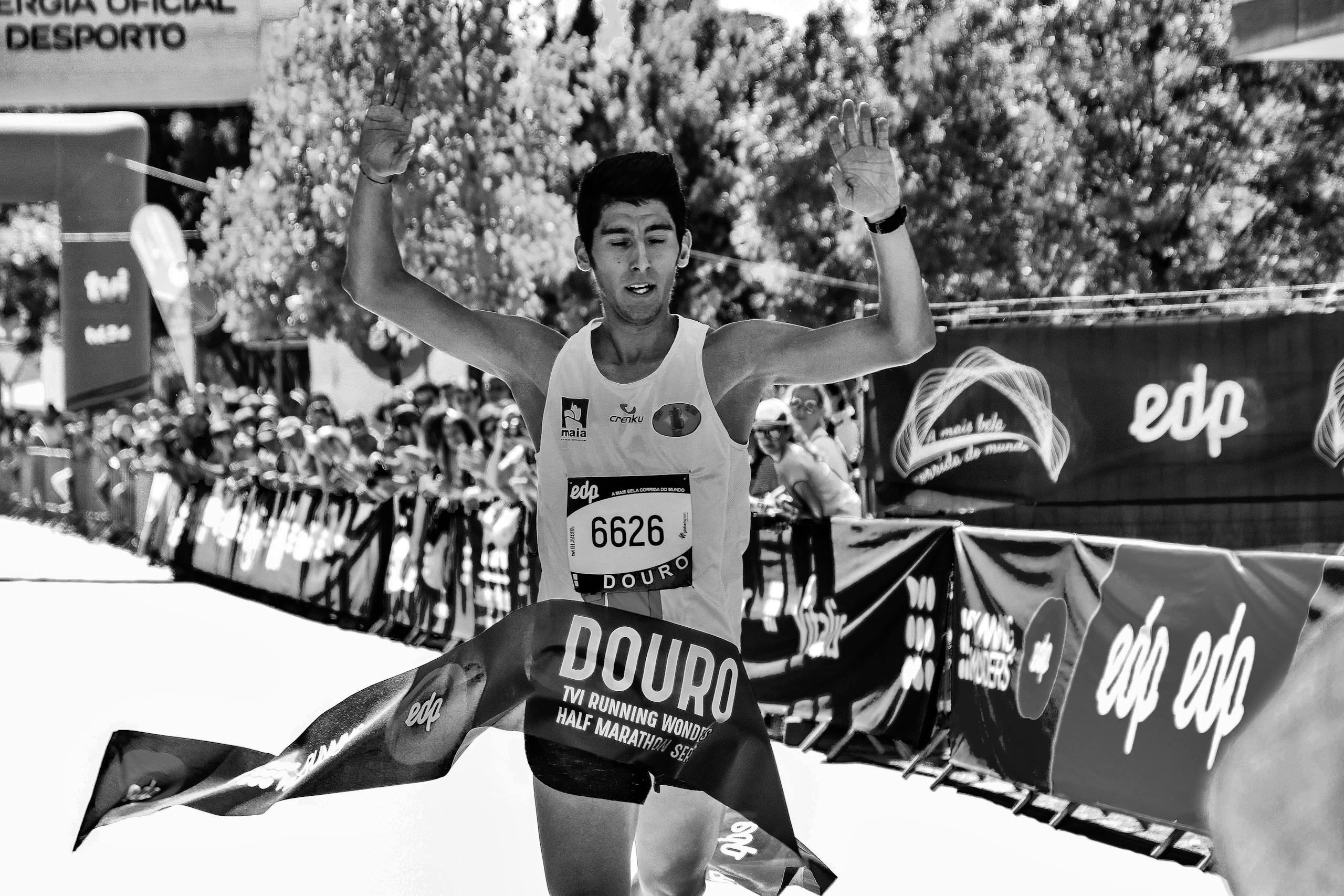 Triumphant athlete crossing the finish line at Douro half marathon in a vibrant race.